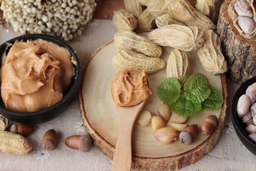 Peanut butter and peanut on wood background.