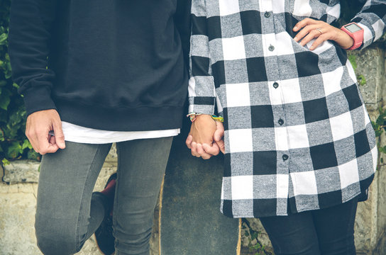 Couple with skateboard holding hands outdoors