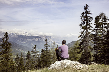 Hiker sitting on rock on a mountain top in alpine landscape