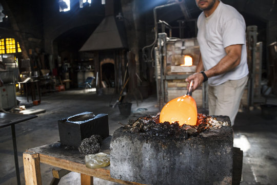 Man putting molten glass in a mold in a glass factory