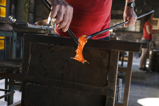 Man working with molten glass using a tweezers in a glass factory