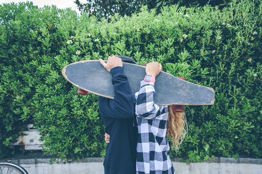 Couple hiding behind skateboard