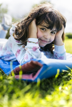 Portrait of smiling little girl lying on airbed on a meadow