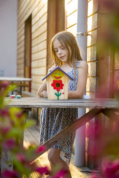 Portrait of girl with painted birdhouse
