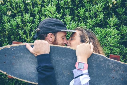 Couple kissing behind skateboard