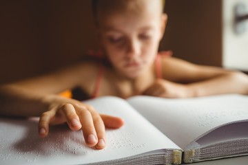 Little girl using his right hand to read braille - obrazy, fototapety, plakaty