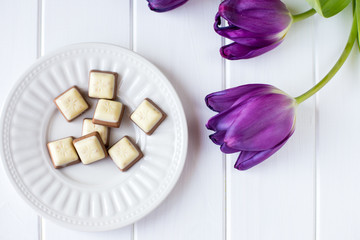 violet tulips on white wooden background with chocolate