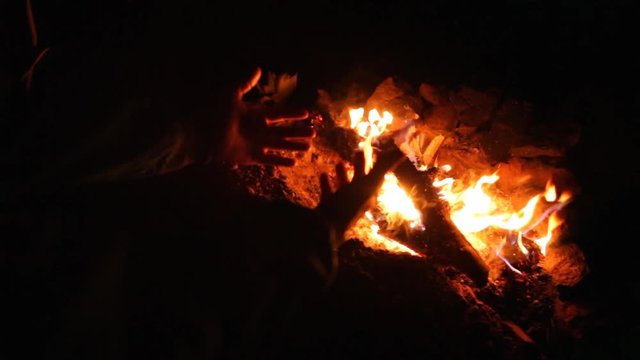 A man warming his hands by a camp fire