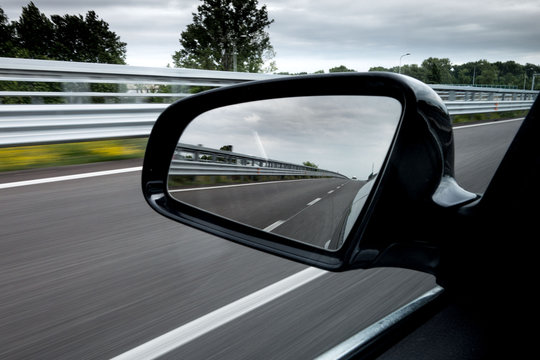 Specchietto retrovisore laterale di una macchina che viaggia in autostrada