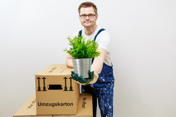 Mann überreicht mit linker Hand eine grüne Pflanze