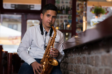 Young gypsy saxophone player.Colored and under exposed photo