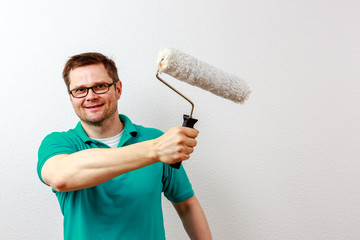 Mann streicht Wand weiß an, closeup