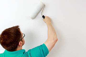 Mann streicht Wand weiß an, closeup