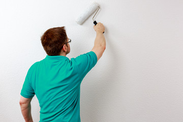 Mann streicht Wand weiß an, closeup