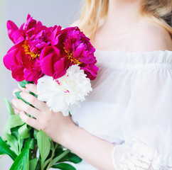 Closeup woman hands holding pink and white peonies