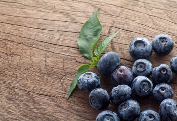 Freshly picked blueberries in wooden background. Juicy and fresh blueberries with green leaves on rustic table.Concept for healthy eating and nutrition