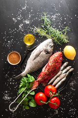 orata, scorfano e sarde con ingredienti per cucinare