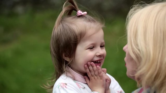 Daughter gives her mother's a big hug. Adorable toddler playing with mother