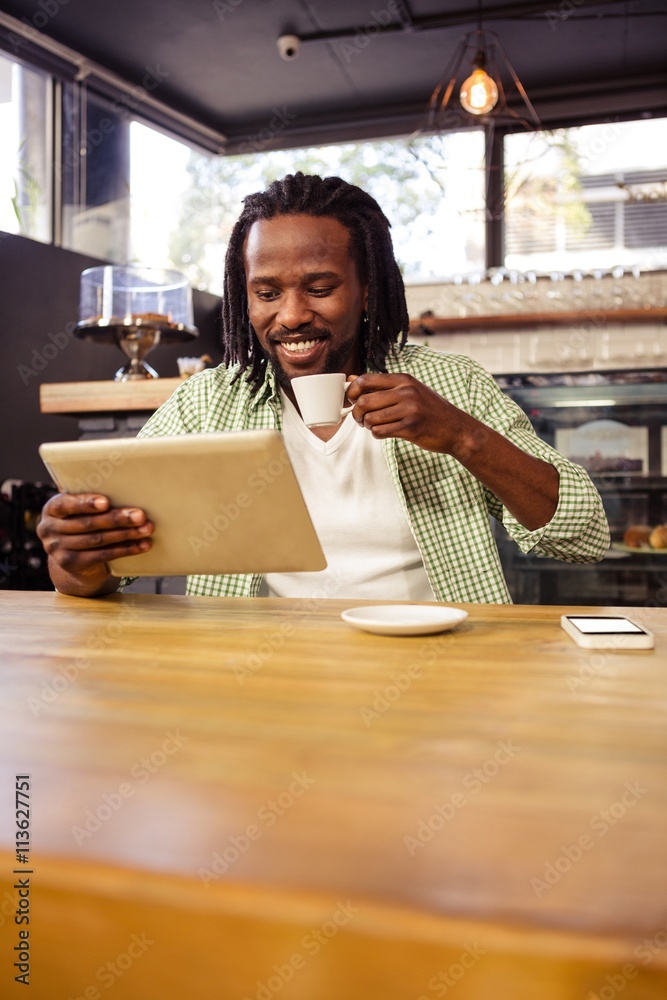 Poster man drinking coffee and using tablet