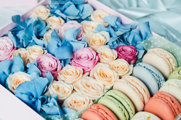 Colorful roses and macaroni in the pink box on the table