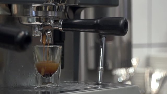Espresso machine makes espresso and it pours into a small cup in slow motion