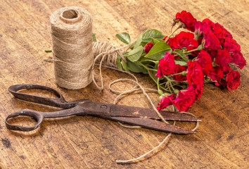 Bouquet of Red Roses, ball of Twine and Old Rusty Scissors on Wo