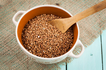 Buckwheat groats in a bowl and wooden scoop