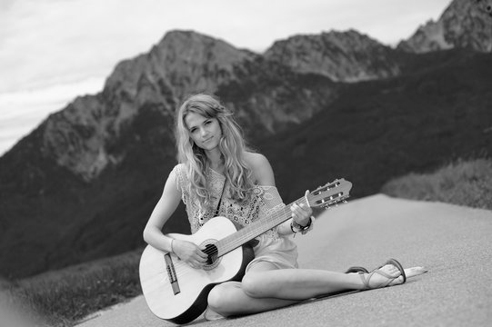 Junge Frau spielt vor dem Hochstaufen auf einer Gitarre