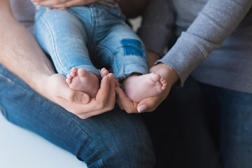 Baby feet on father and mother hands, close-up