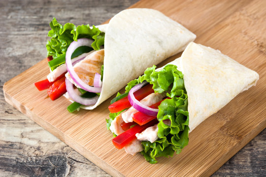 Mexican chicken fajitas with peppers lettuce and onion on a rustic wooden table

