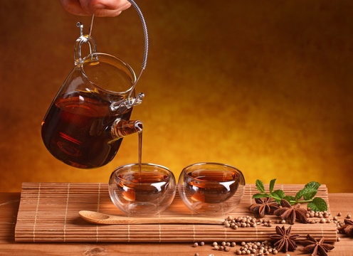 versare tisana di coriandolo, anice stellato e menta - sfondo giallo