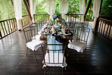 Wedding restaurant decor, rustic, boho style. Glasses, a wooden table, a blue tablecloth.