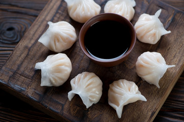 Rustic wooden serving board with steamed dim sums, closeup