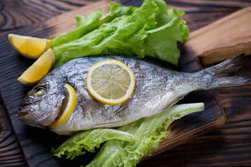 Close-up of baked dorado served with lemon and green salad