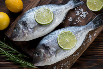 Above view of two raw sea breams with condiments, close-up