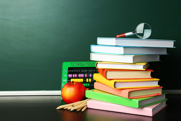 School books on desk near chalkboard