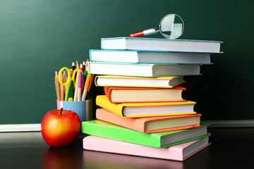 School books on desk near chalkboard