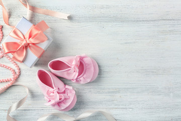 Beautiful composition with baby booties and gift box on wooden background