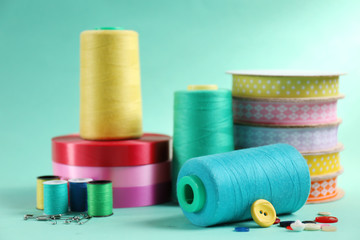 Many ribbons and sewing accessories on color background