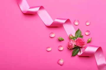 Fresh roses with ribbon on pink background
