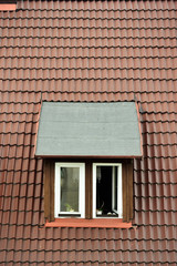 Okno z butami na parapecie w brązowym dachu