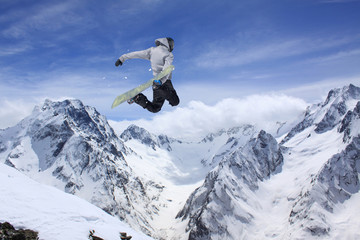 Fototapeta na wymiar Snowboarder making high jump in cloudy sky.