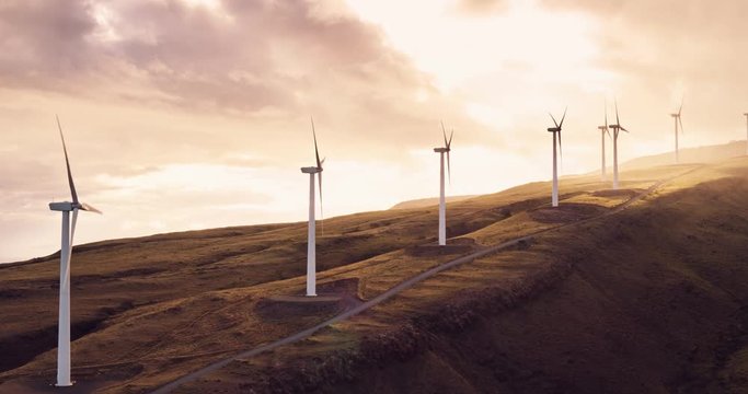 Aerial view of windmills turning at sunset, wind power turbines generate clean renewable energy