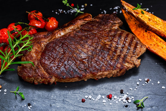 Grilled Beef Sirloin Steak on blue stone background, with vegetables.