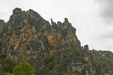 Fototapeta na wymiar Eroded rocks in mountains against gray cloudy sky background