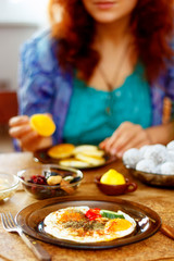 breakfast table setting with scrambled eyes and girl on the background.