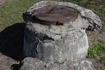 Manhole with the cover on the high concrete basement