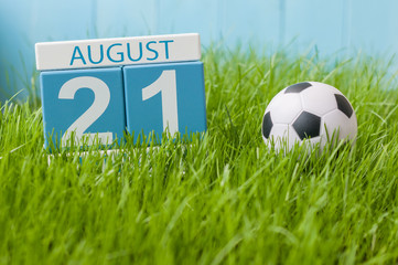 August 21st. Image of august 21 wooden color calendar on green grass lawn background with soccer ball. Summer day. Empty space for text