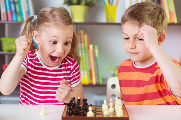 Two cute children playing chess