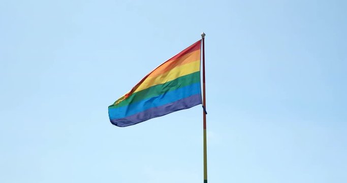 Gay pride flag mid screen against blue sky